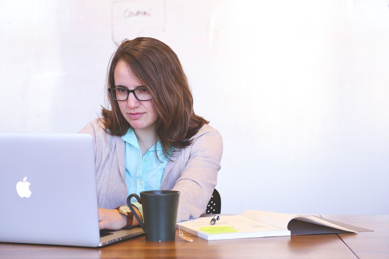 paralegal working at computer with cup of coffee and book open
