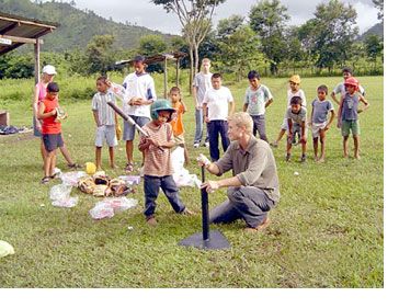 Peace Corps worker helping chilren play t-ball