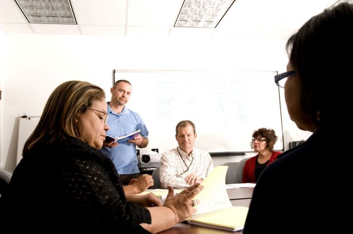 health services administrator sitting at a desk, looking at document, and talking to others