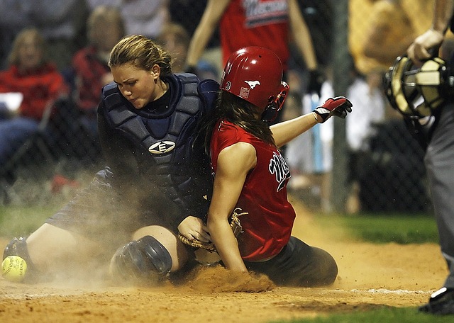 woman sliding home into catcher in softball game and knocking ball free