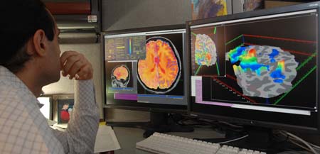 neuroscientist looking at brain pictures neuroscientist looking at pictures of brains on two computer screens
